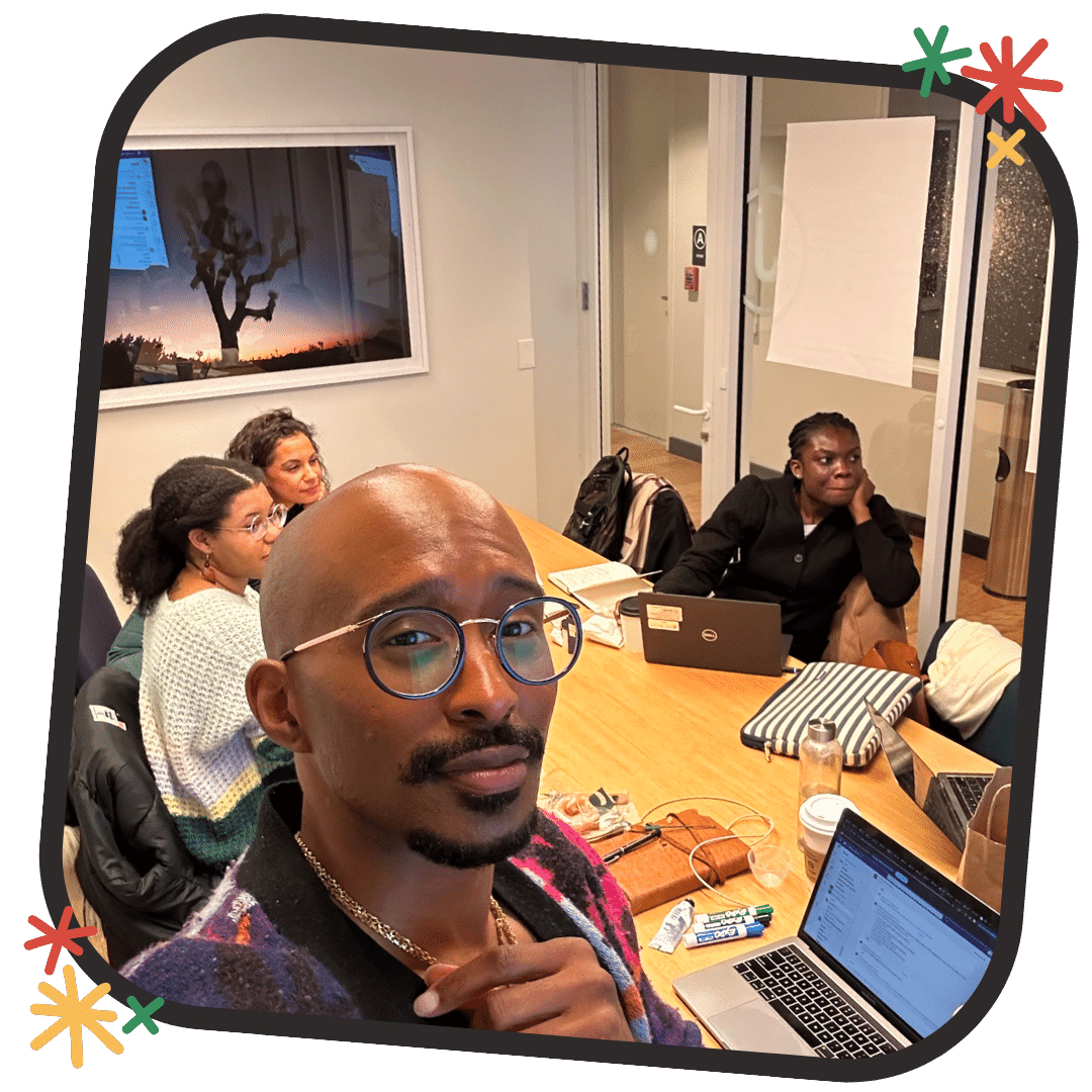 This is a photo in black, red, yellow, and green decorated frame from the Black to the Future workgroup session with Black indentified ETRians in a office room working together. 