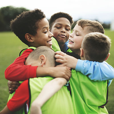 A group of boys wrestles on a playing field.