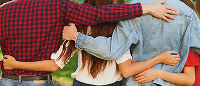 Group of friends, from the back, with their arms around each other