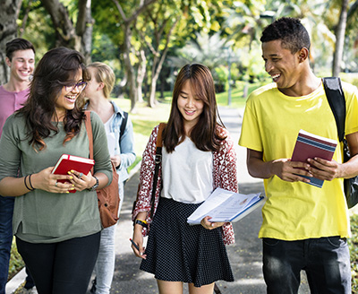 Group of friends walking along a park-like path, smiling and engaged with one another