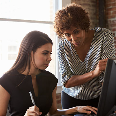 Two women work on a computer together.