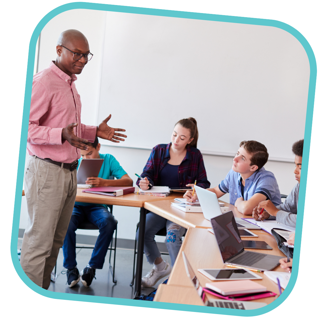 This is a photo in a light teal frame. In the photo is an adult teaching a group of young people in a classroom setting. 