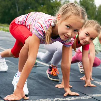 A few young blonde girls crouched in the starting position for a race.