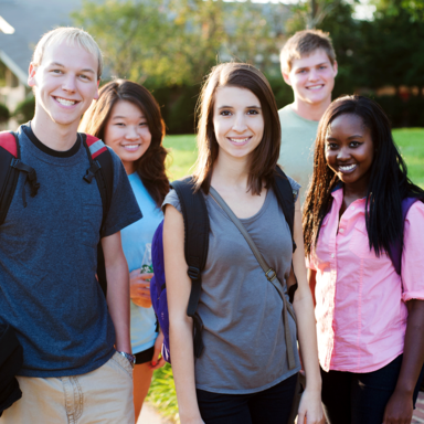 A group of young people with backpacks smiling at the camera.