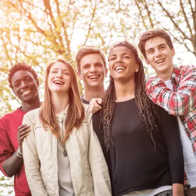 A group of young people with their arms around each other, laughing.